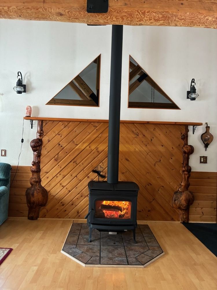 Black wood stove with fire burning in a log cabin living room