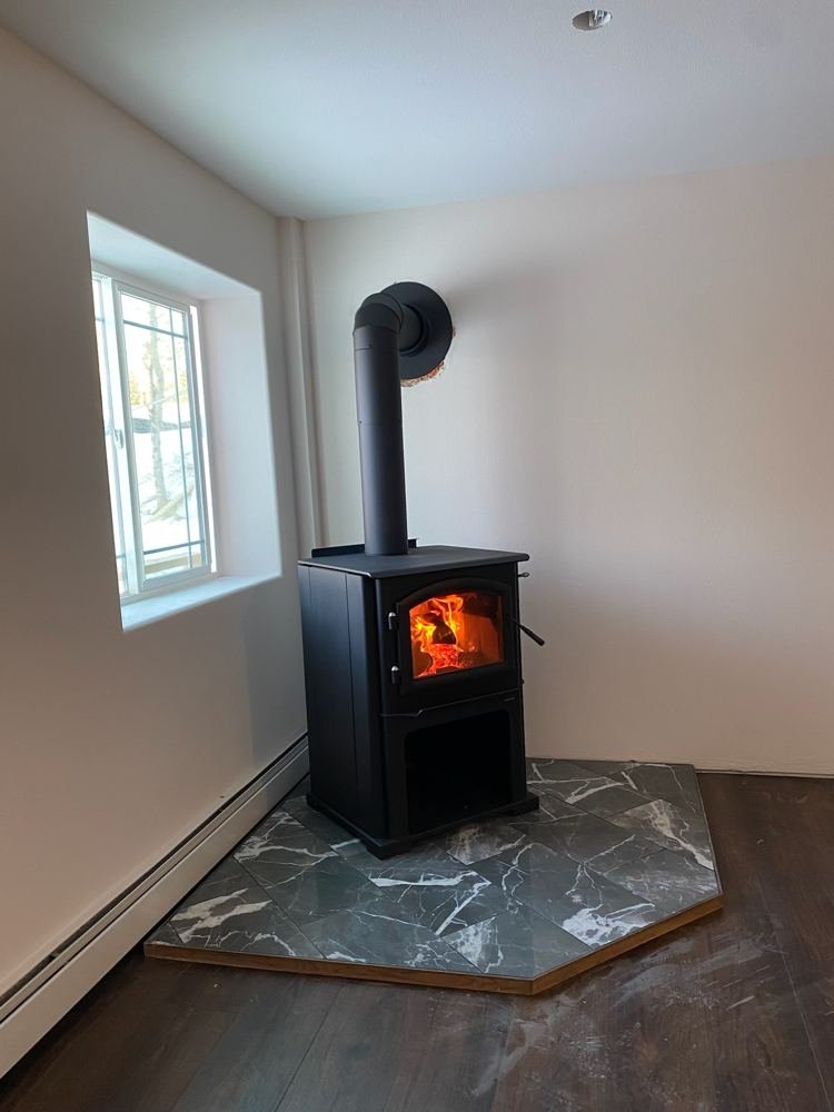 Newly installed wood stove with first fire burning, clean bright room